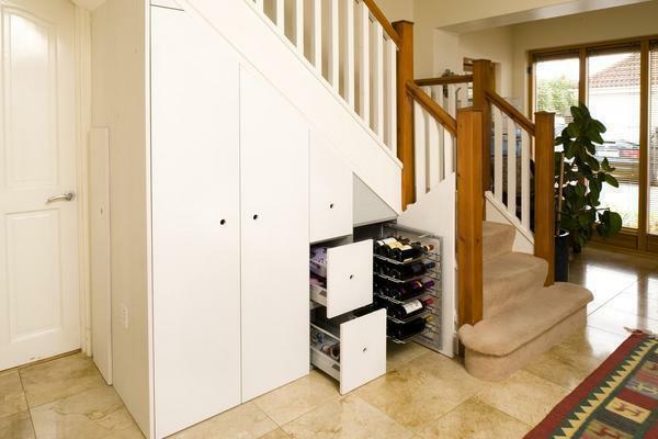 Menempatkan lemari di bawah tangga, Anda dapat secara signifikan menghemat ruang di apartemen