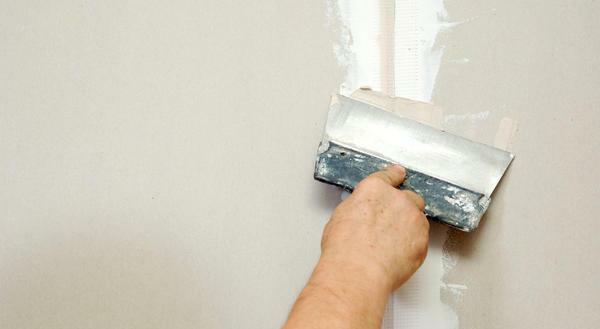 Platta spacklet på väggen, experter rekommenderar ett brett spatel