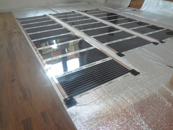 Atrakcyjny design laminatu w mieszkaniu bardzo przyjemny sposób połączony z instalacją ogrzewania podłogowego.