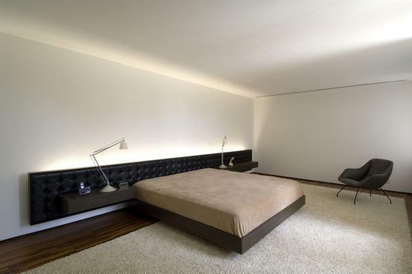 The bedroom in the style of minimalism is furnished with furniture so as to obtain a maximum of free space