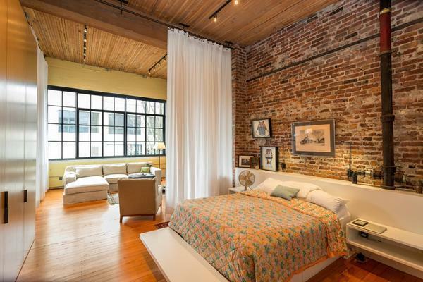 Brutalumas stiliaus Loft yra ideali gyvenamasis kambarys su miegamojo