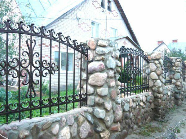 Geschmiedete Zäune für Häuser mit Steinsäulen sehen sehr authentisch