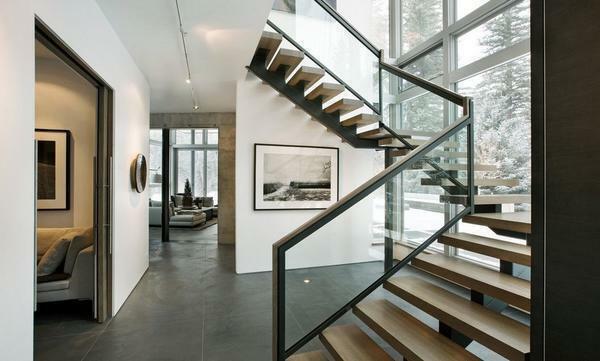Make the interior of the living room original and refined with the help of a creative wooden staircase with glass rails
