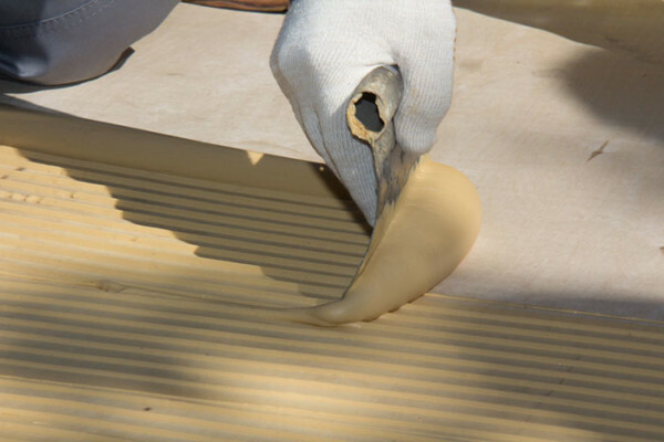 Applicare l'adesivo per la posa di tavole in legno