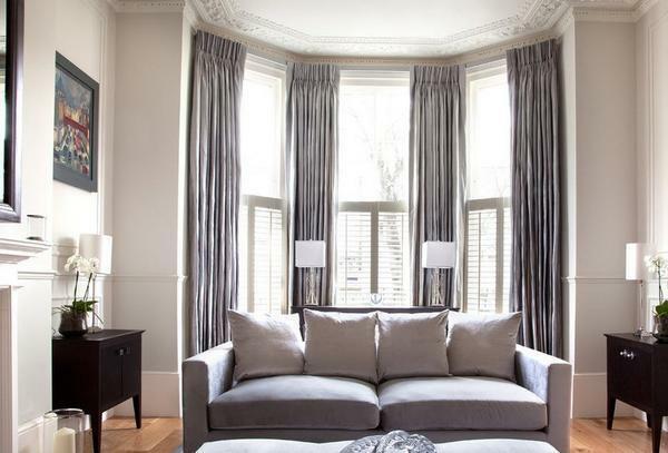 Curtains on the bay window in the living room should nicely and organically complement the interior of the room