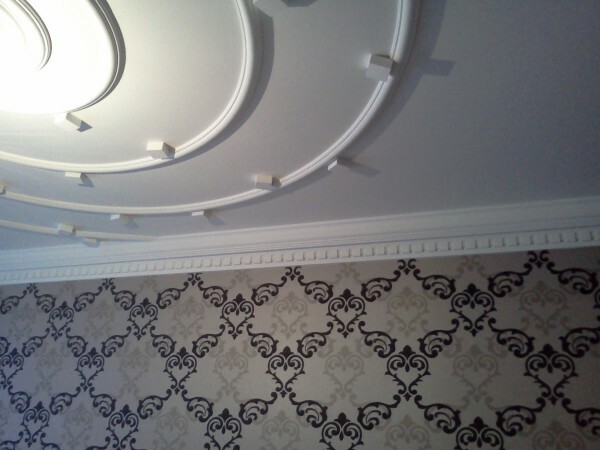 Neat plaster decorations, combined with fabric wallpaper