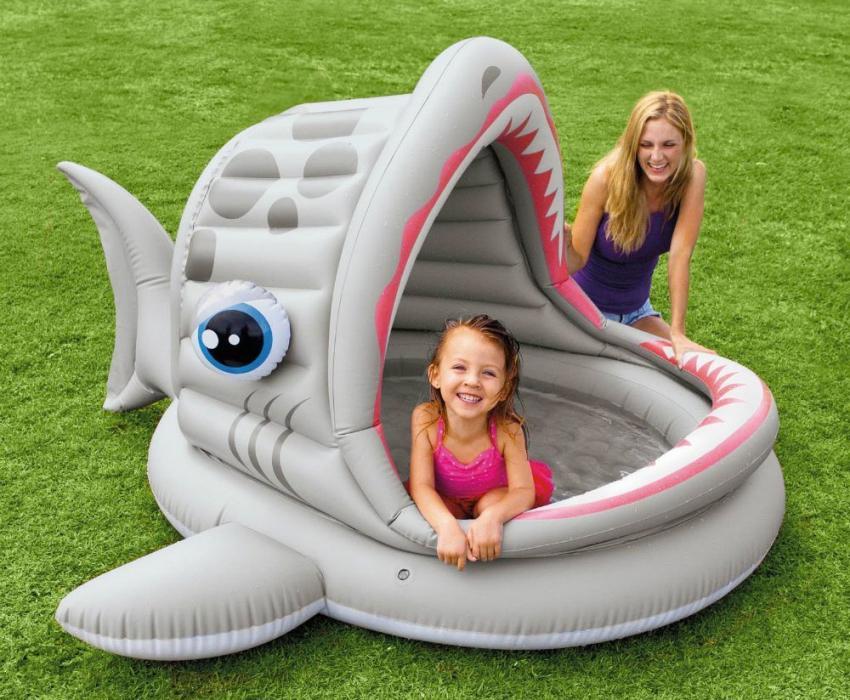 Une piscine pour enfants avec un abri gonflable sous la forme de poissons « béant »